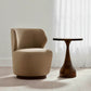 Beige armchair and wooden side table in a minimalistic room with white curtains.