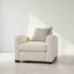 Beige armchair with a striped pillow in a minimalistic room.
