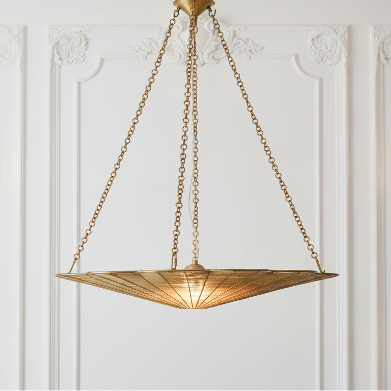 Gold pendant light fixture hanging against a white wall with decorative molding.