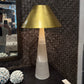 Decorative lamp with gold shade and marble base on a patterned surface