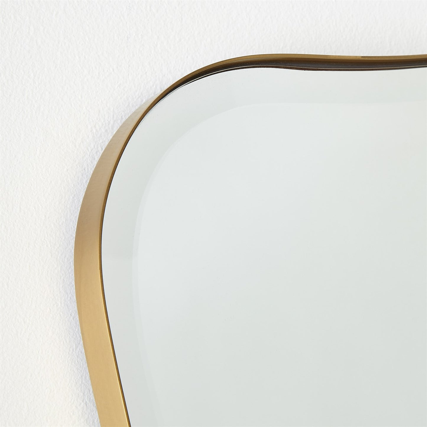 Round mirror with a gold frame on a white wall