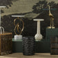 Decorative sculptures and vases on a textured surface with a scenic wall mural in the background
