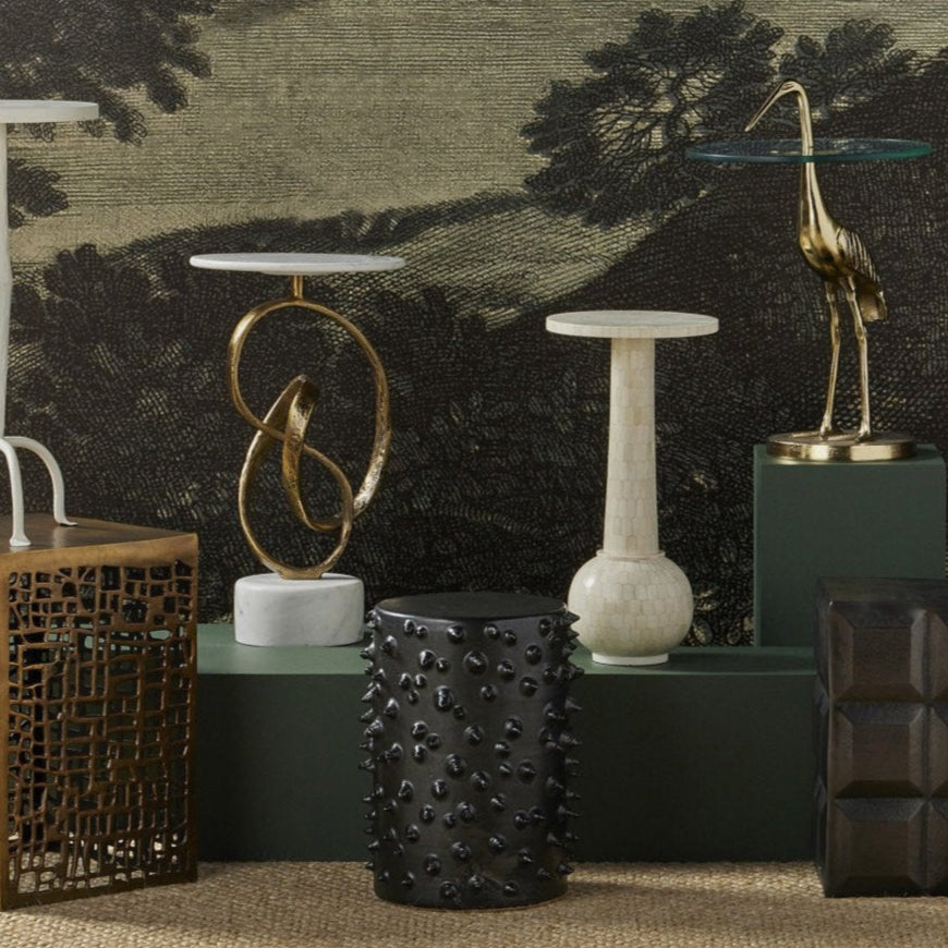 Decorative sculptures and vases on a textured surface with a scenic wall mural in the background