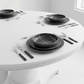 Round white table with black dinnerware set in a minimalistic room.