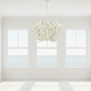 Modern chandelier hanging in a bright room with large windows.