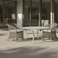 Outdoor patio set with wicker chairs and table on a tiled patio.