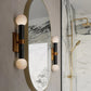 Round mirror with spherical sconces on a marble wall