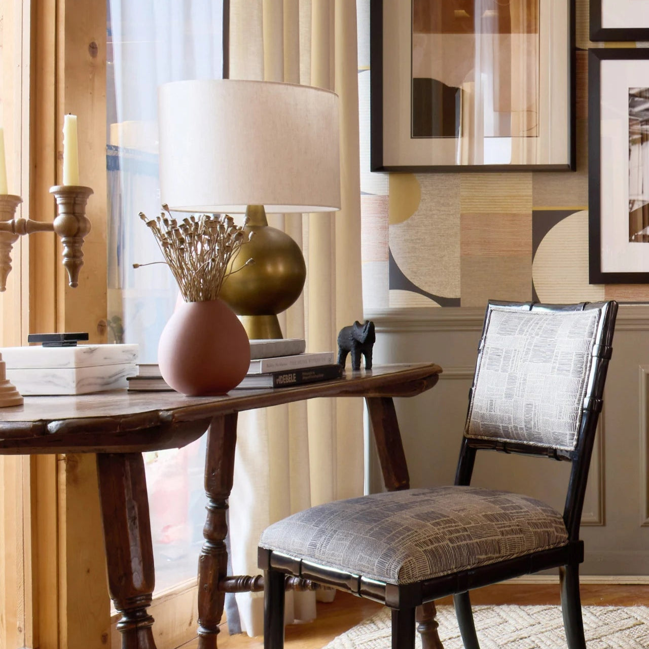 Wooden table with lamp and decor items in a room with framed art on the wall.