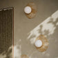 Three wall-mounted lights on a beige wall with a framed artwork to the left.