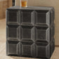 Geometric patterned side table with a glass of amber liquid on a beige surface.