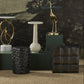 Decorative sculptures and vases on a textured surface with a scenic wall mural in the background