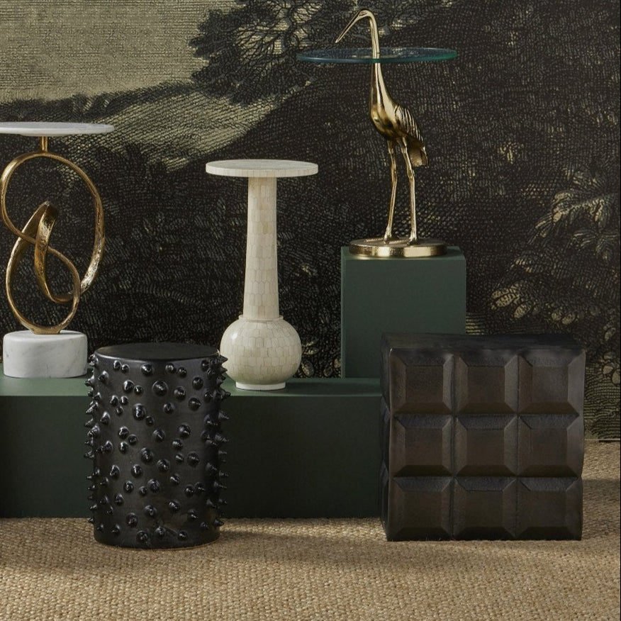 Decorative sculptures and vases on a textured surface with a scenic wall mural in the background