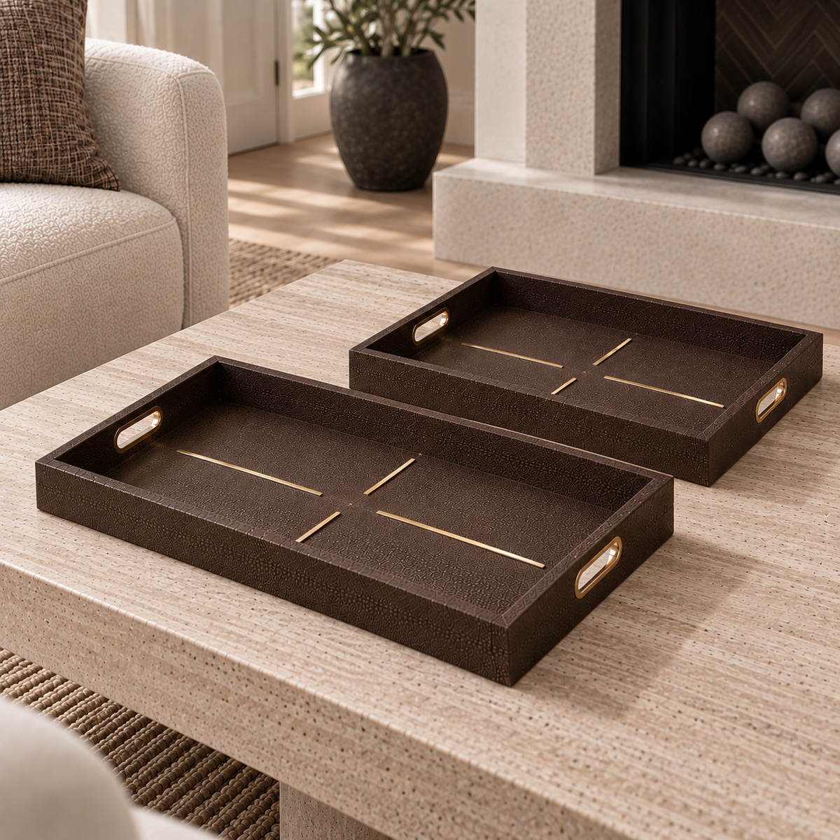 Two dark brown textured rectangular serving trays with gold linear accents and side handles, displayed on a light wood coffee table in a modern living room setting.