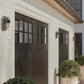 Brown garage door with glass panels on a white brick wall.