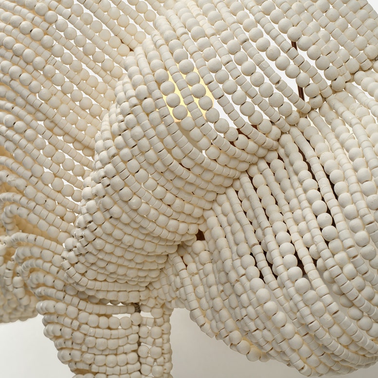 Close-up of a white beaded elephant sculpture against a light background