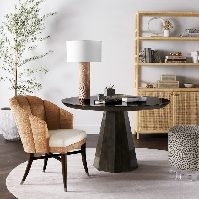 Modern dining room with a round black table, beige chair, and decorative elements.