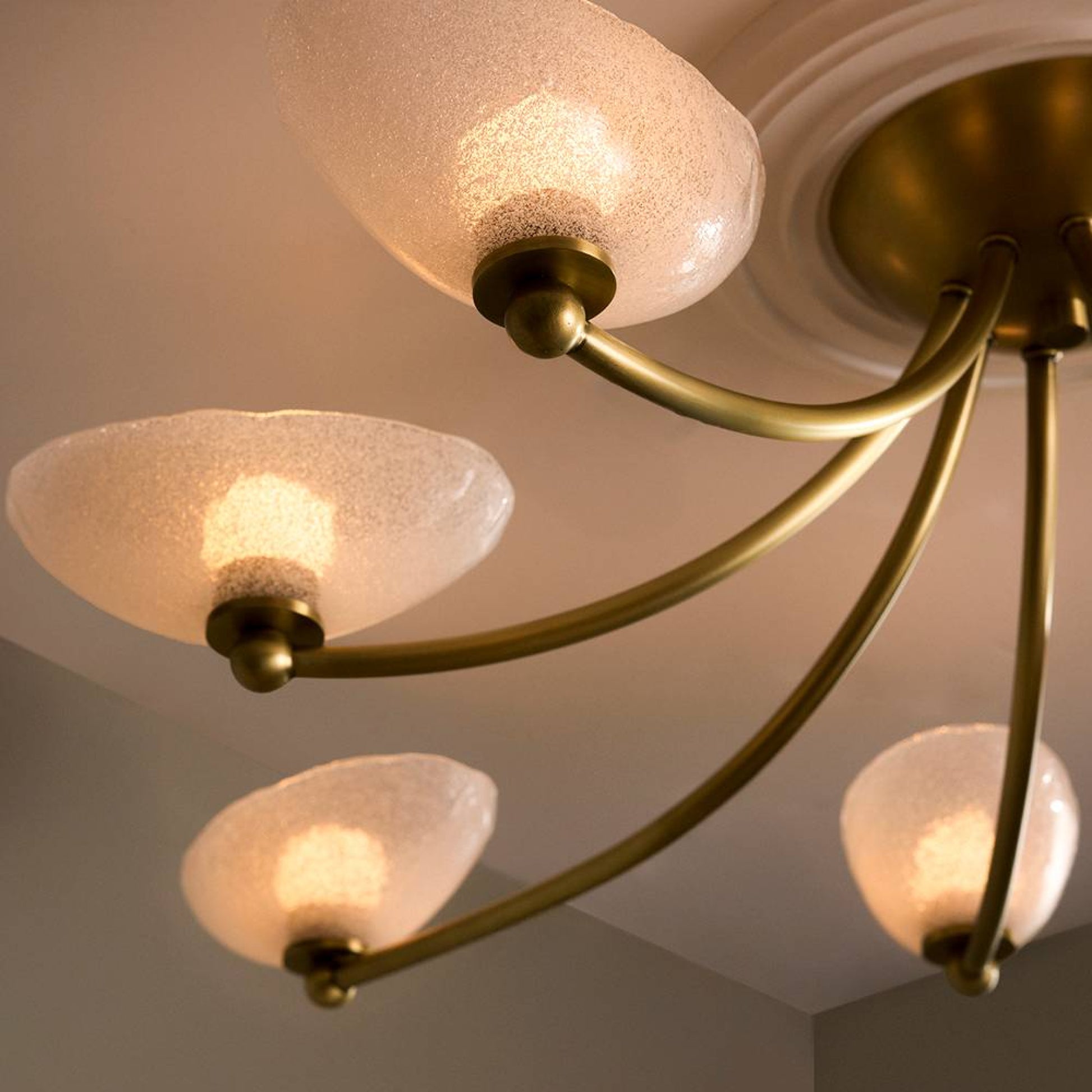 Gold chandelier with frosted glass shades on a ceiling.