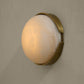 Wall-mounted light fixture with a gold frame and white glass on a beige wall.