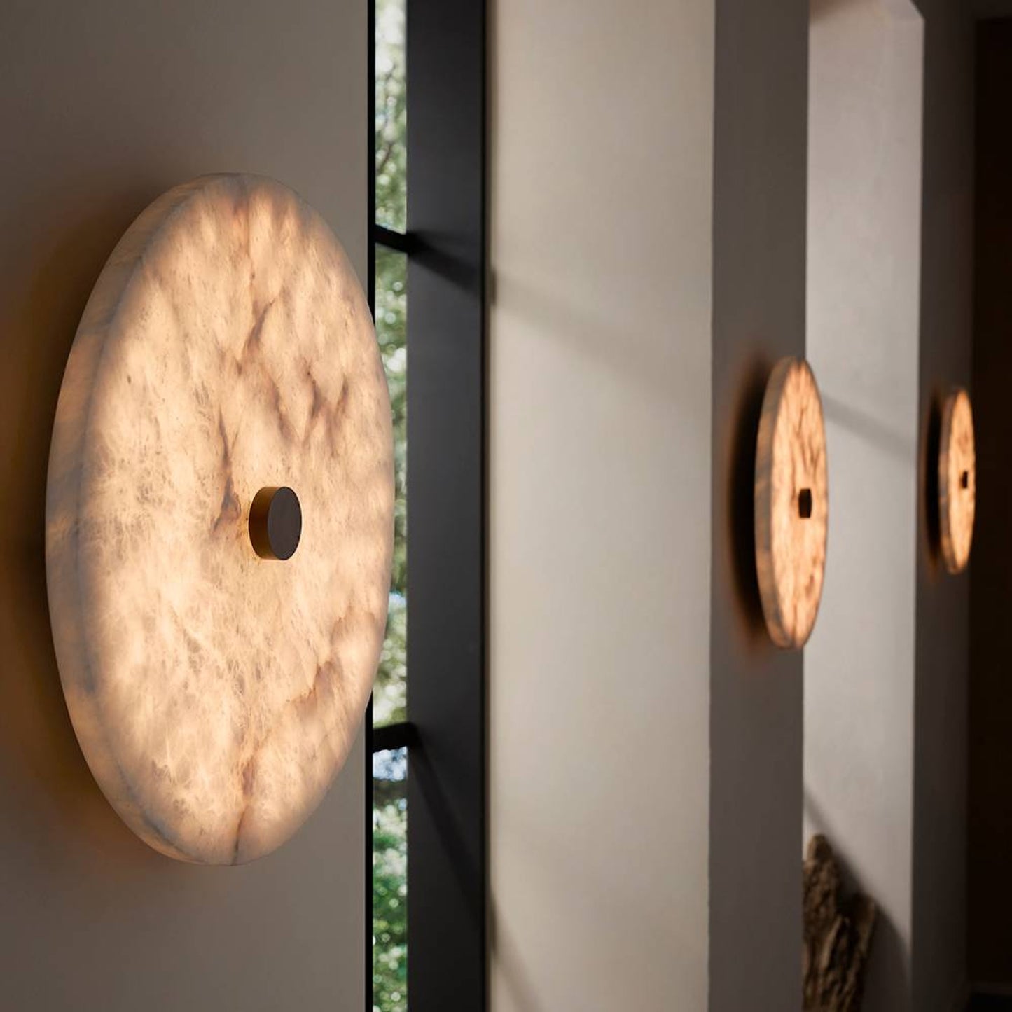 Round wall lights on a neutral wall with a window in the background