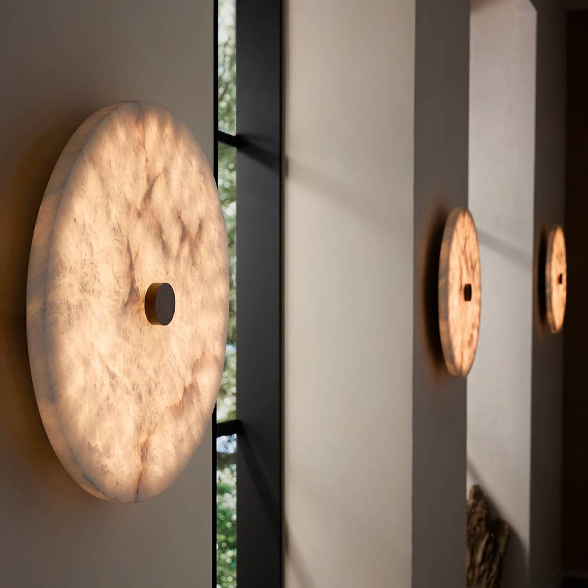 Round wall lights on a neutral wall with a window in the background