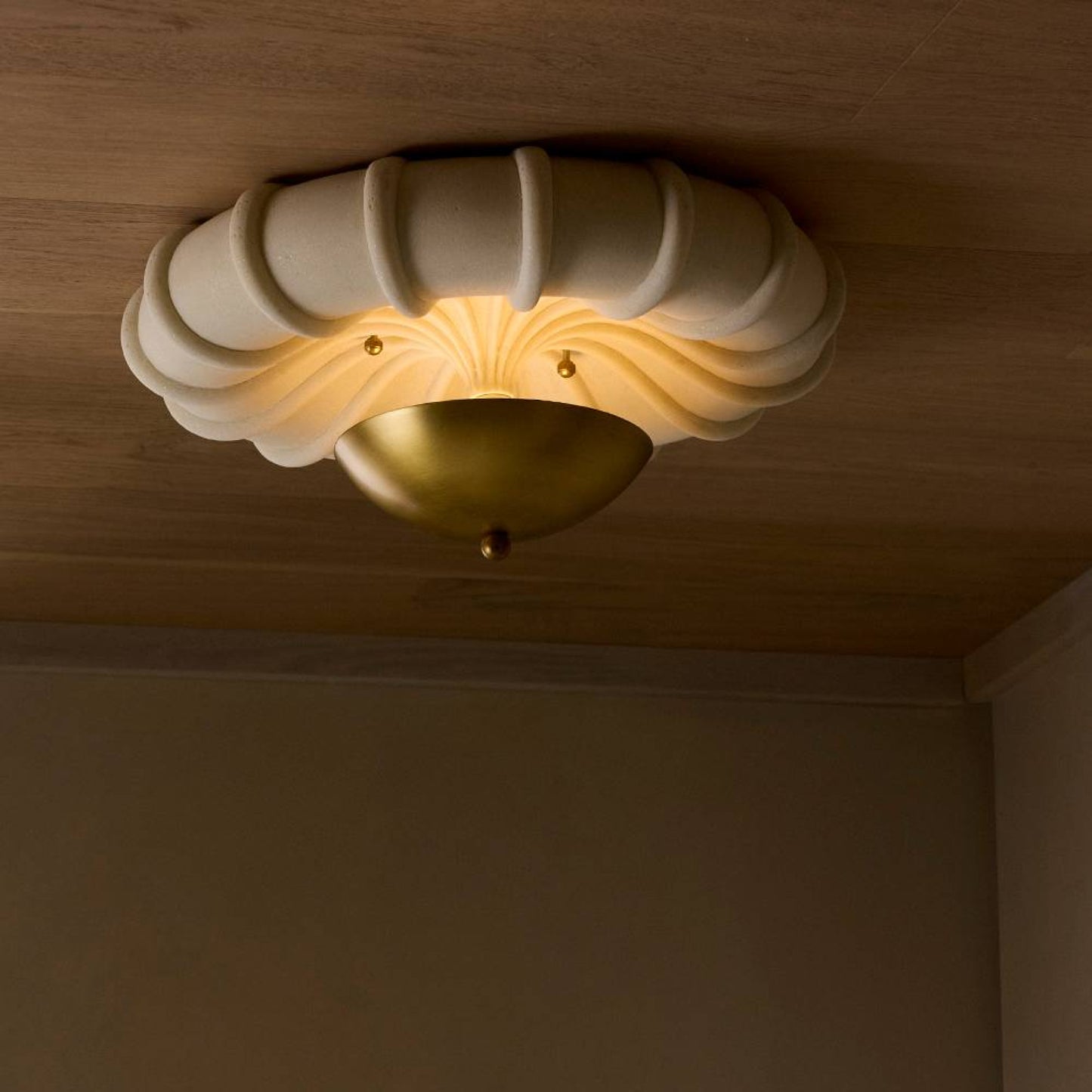 Decorative ceiling light fixture with a warm glow on a wooden ceiling.