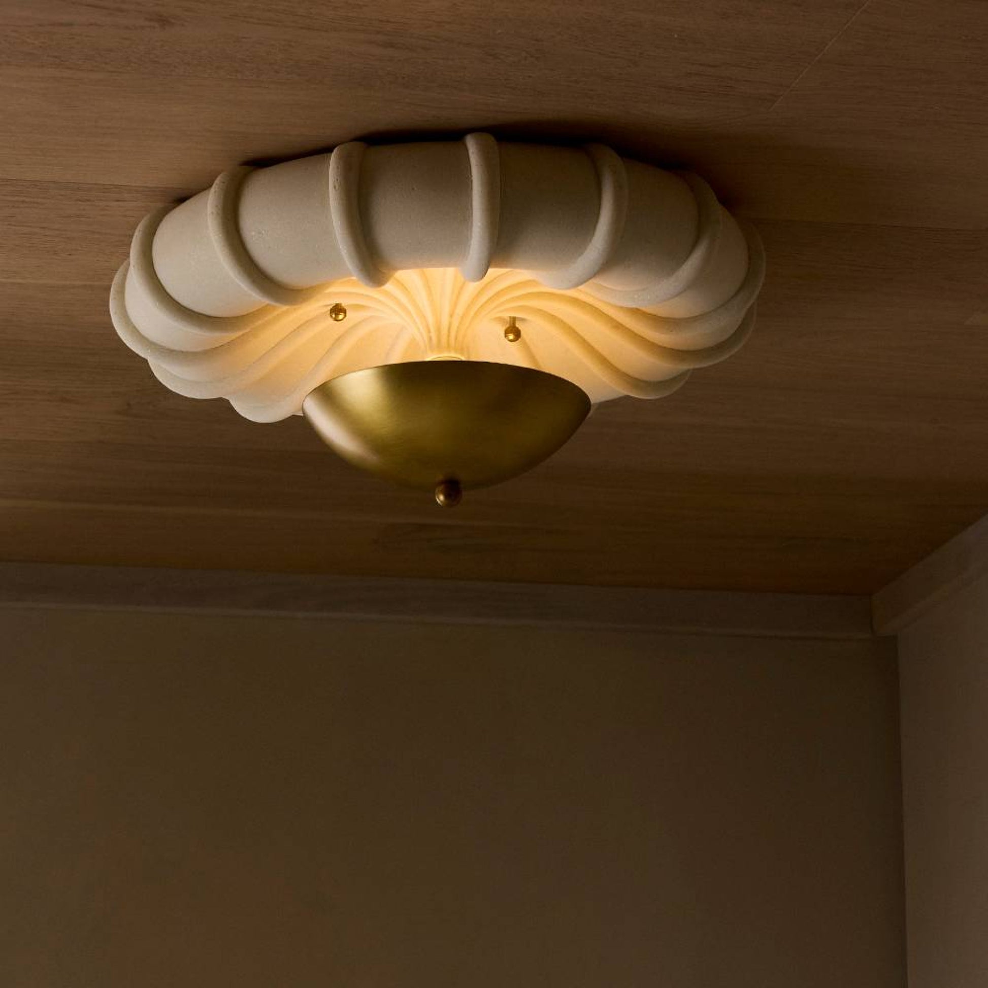 Decorative ceiling light fixture with a warm glow on a wooden ceiling.