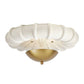 Ceiling light fixture with white shell-like shade and gold base on a white background