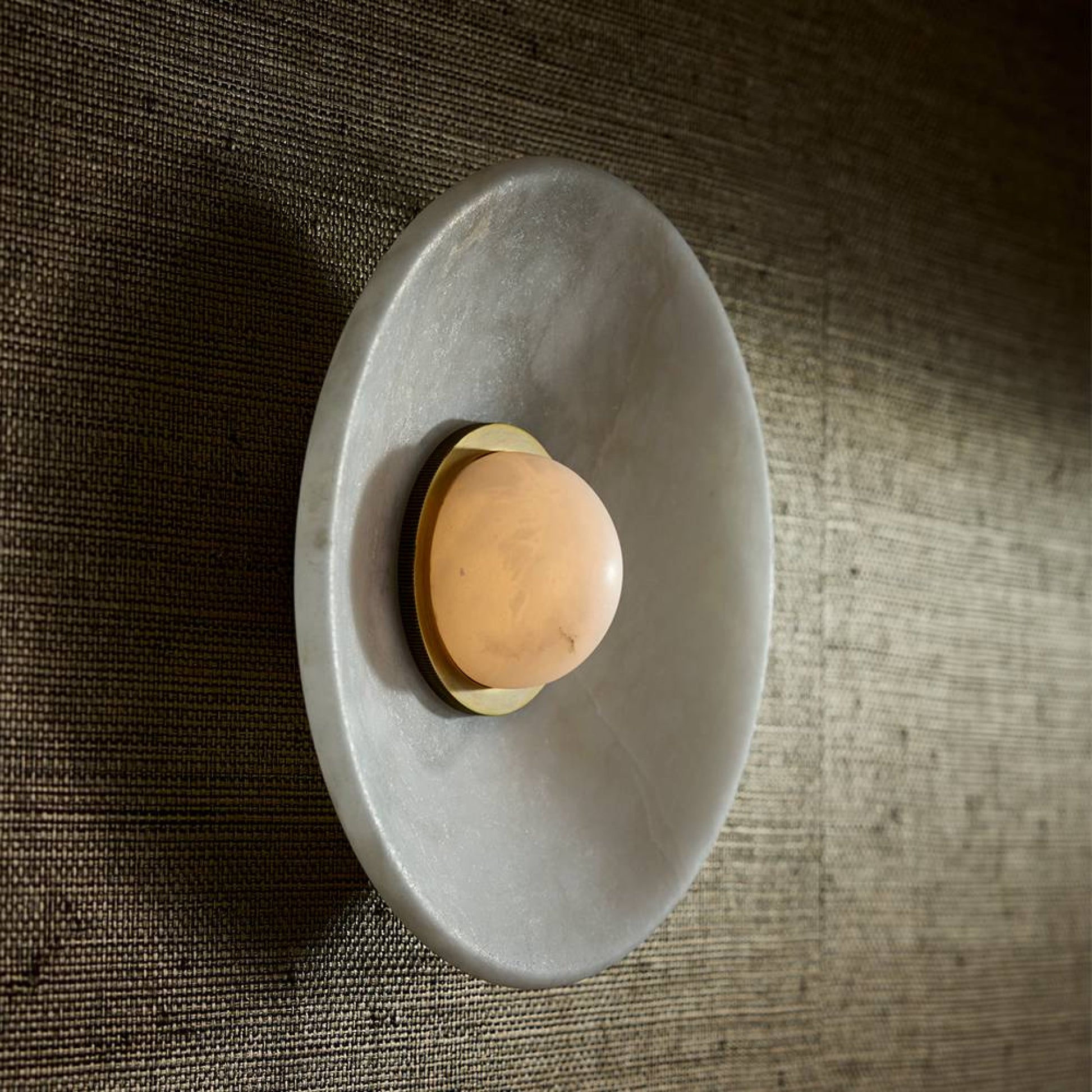 Round gray stone dish with a single brown egg on a textured brown surface