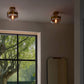 Two ceiling lights with glass shades in a room with a window showing greenery outside.