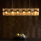 Modern chandelier with glass shades on a dark wall.