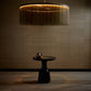 Modern pendant light with a textured shade above a black table against a textured wall.
