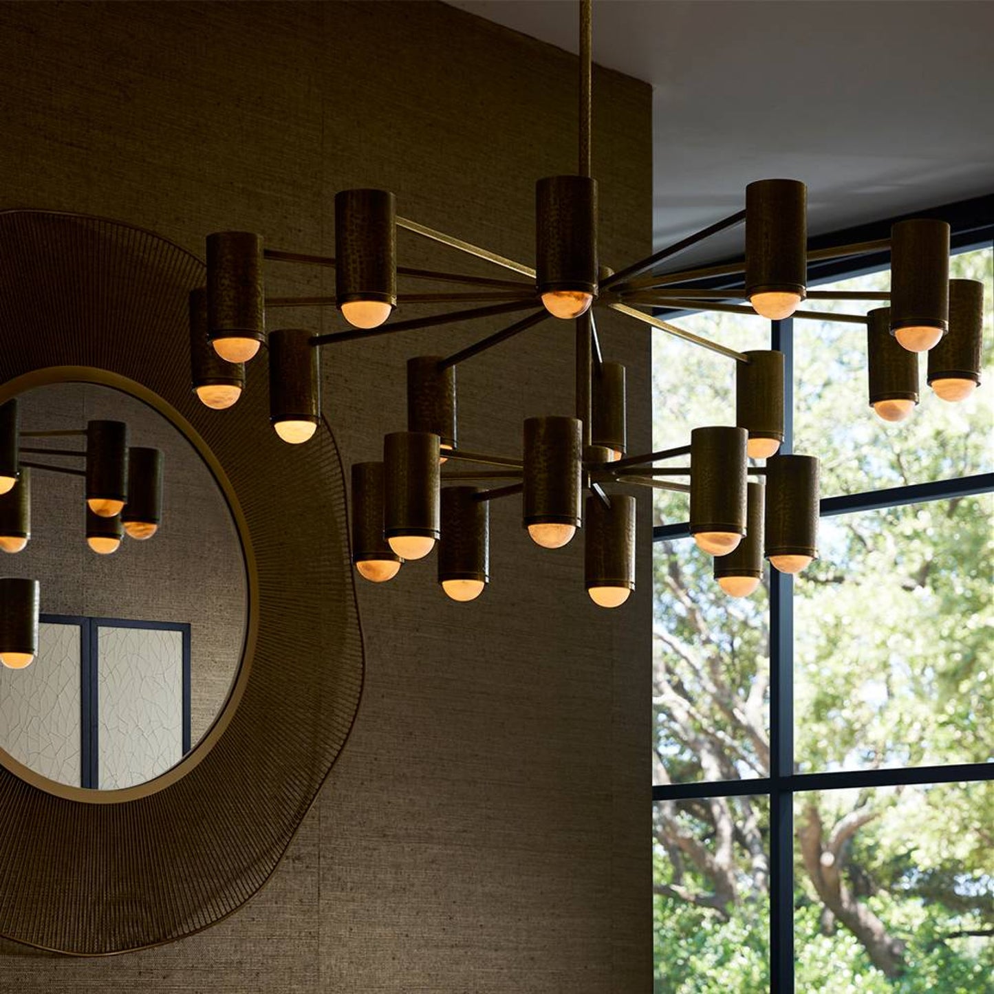 Modern chandelier hanging in a room with a mirror and window view