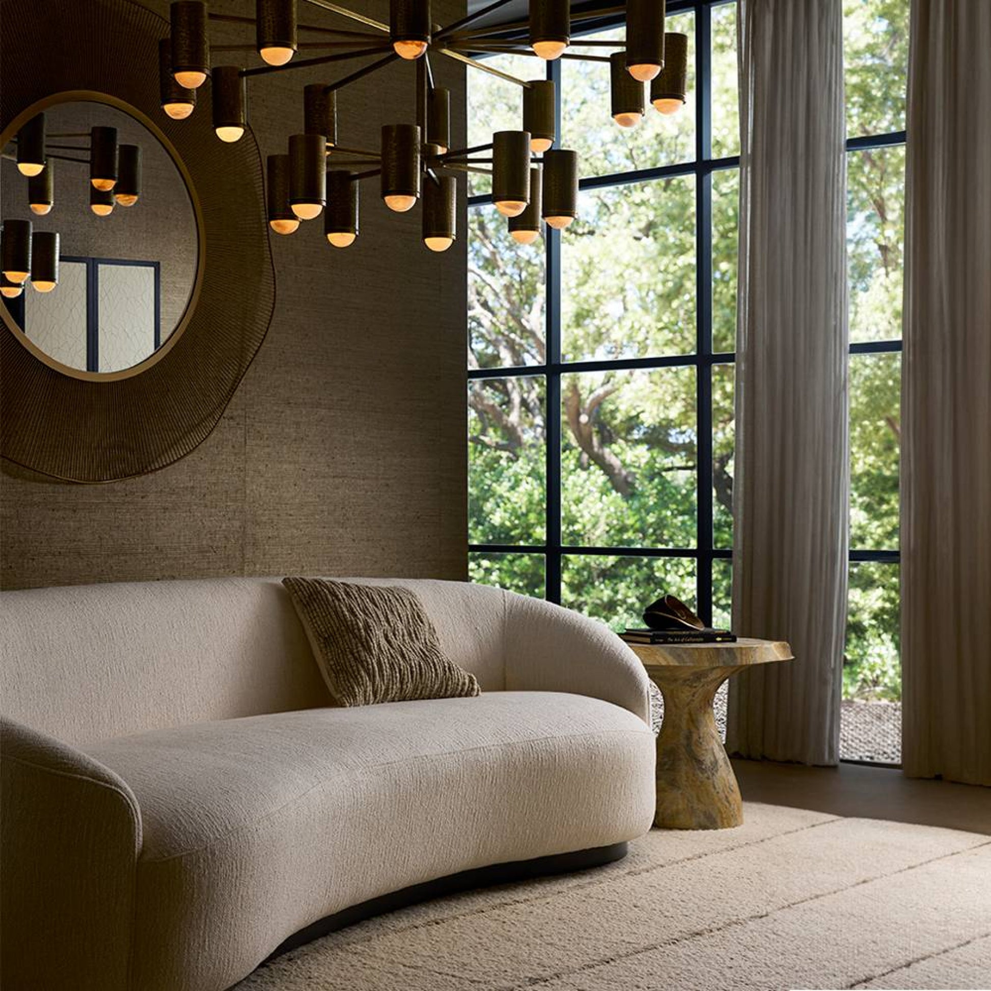 Modern living room with a beige sofa, decorative mirror, and chandelier.