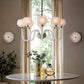 Modern chandelier hanging above a table with decor items in a room with large windows.