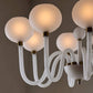 Close-up of a modern chandelier with white glass shades and gold accents.