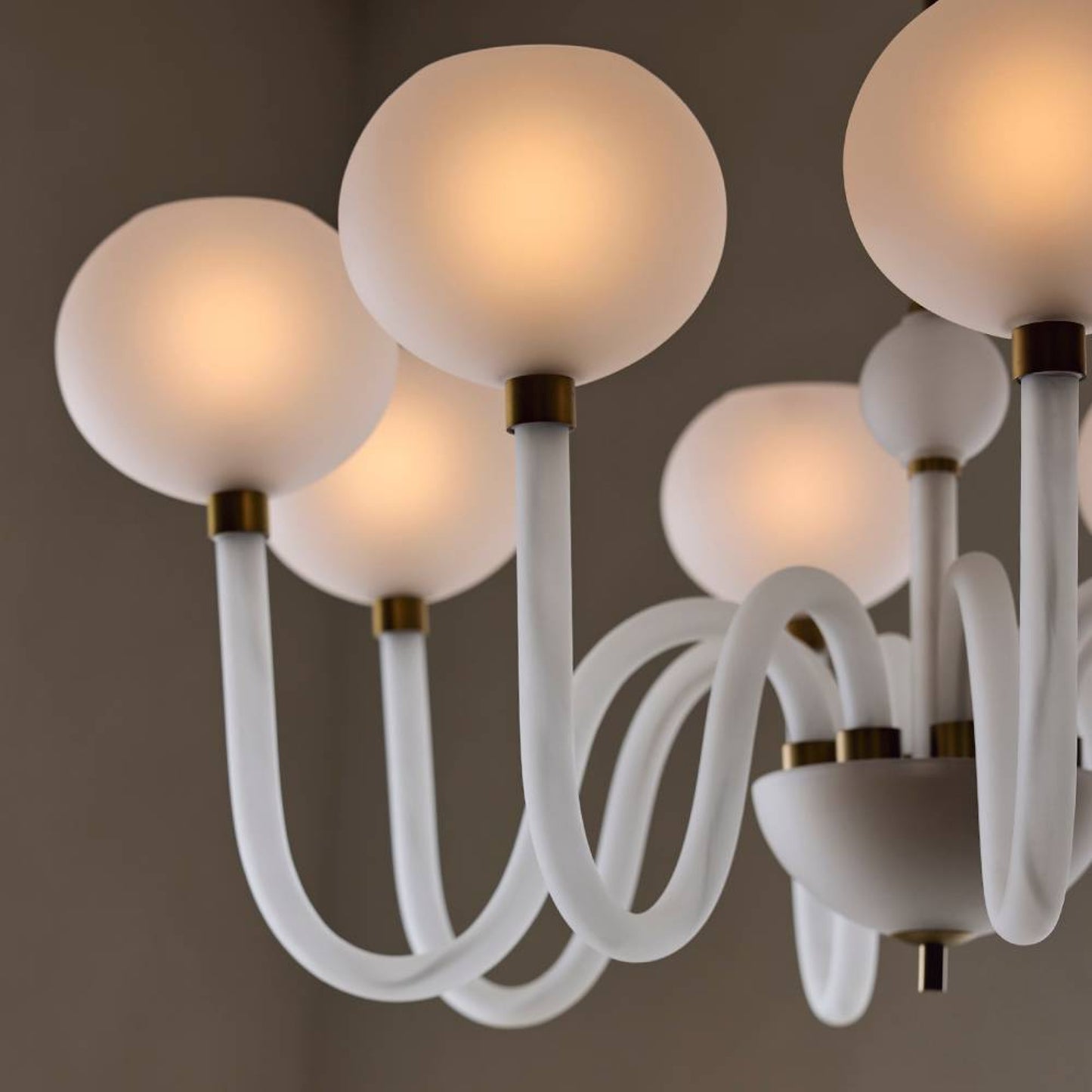 Close-up of a modern chandelier with white glass shades and gold accents.