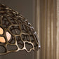 Decorative bronze lampshade with intricate design against a neutral background