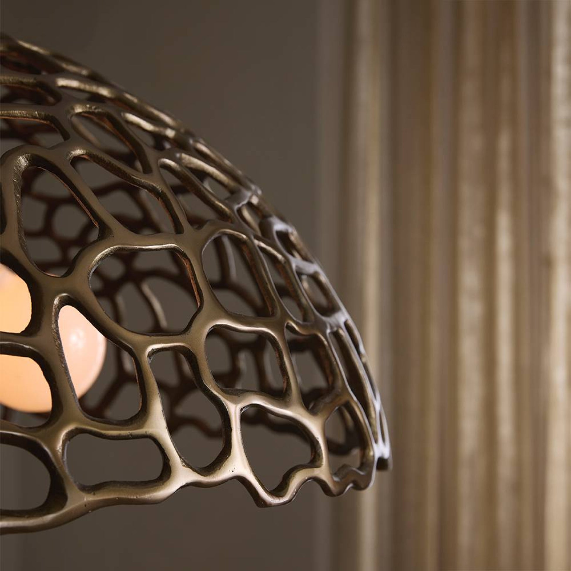 Decorative bronze lampshade with intricate design against a neutral background
