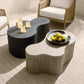 Two modern coffee tables with a bowl of fruit and glasses on a textured floor.