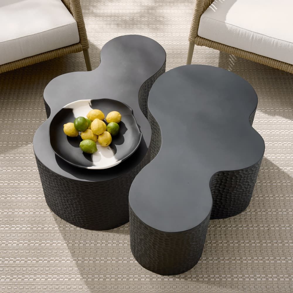 Modern black wicker coffee table with fruit bowl on a textured floor
