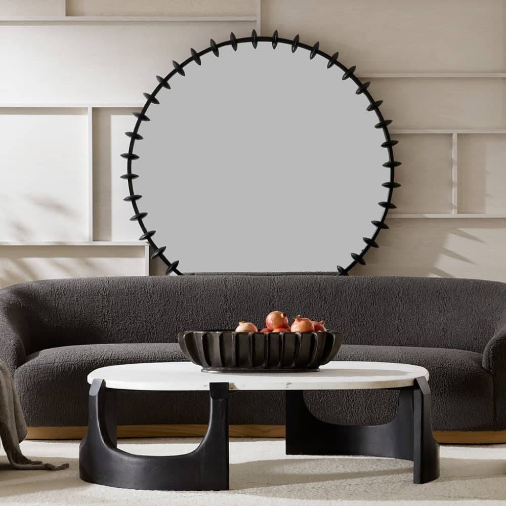 Modern living room with a round mirror, gray sofa, and marble coffee table.