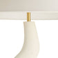 Close-up of a lamp with a white shade and gold fixture on a white background