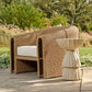 Woven outdoor chair with white cushion and matching side table on a patio