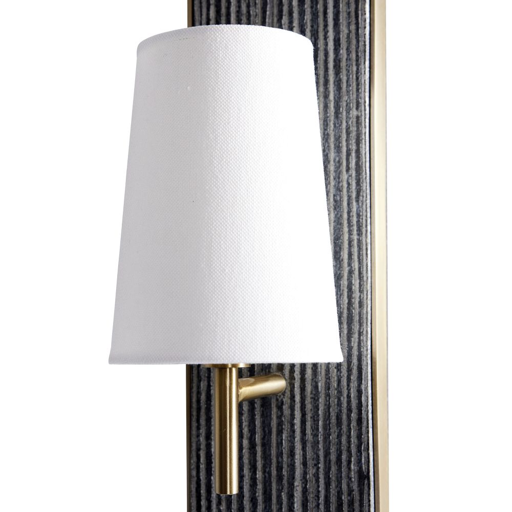 Wall-mounted light fixture with white shade and gold fixture against a textured wall.