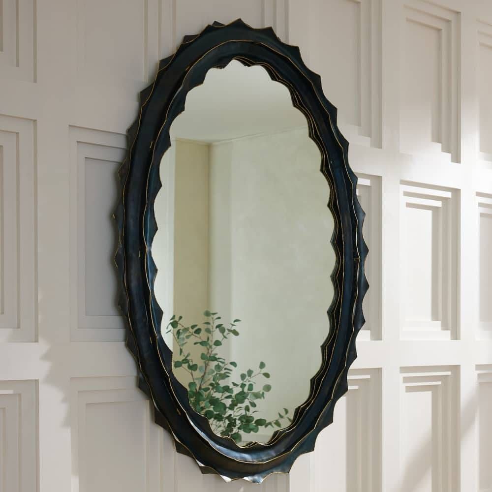 Decorative oval mirror with scalloped edge on a paneled wall