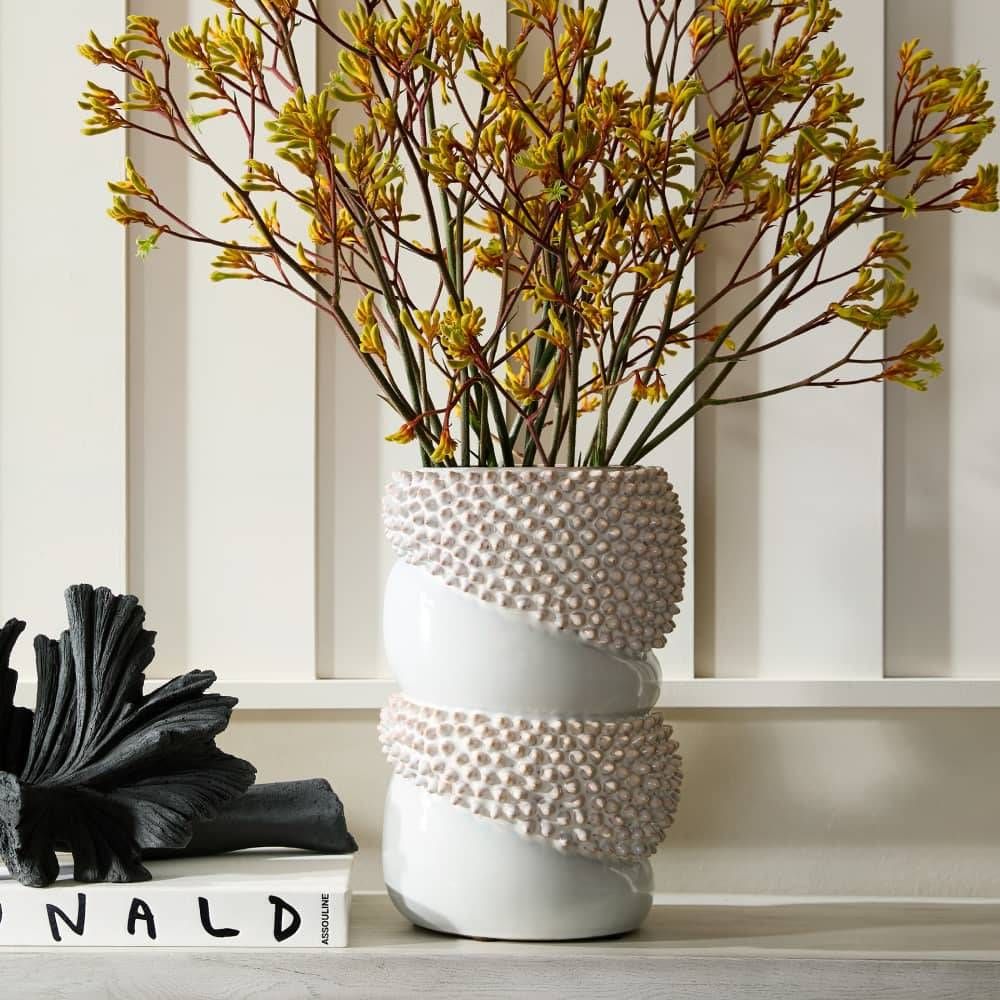 White textured vase with dried flowers on a shelf