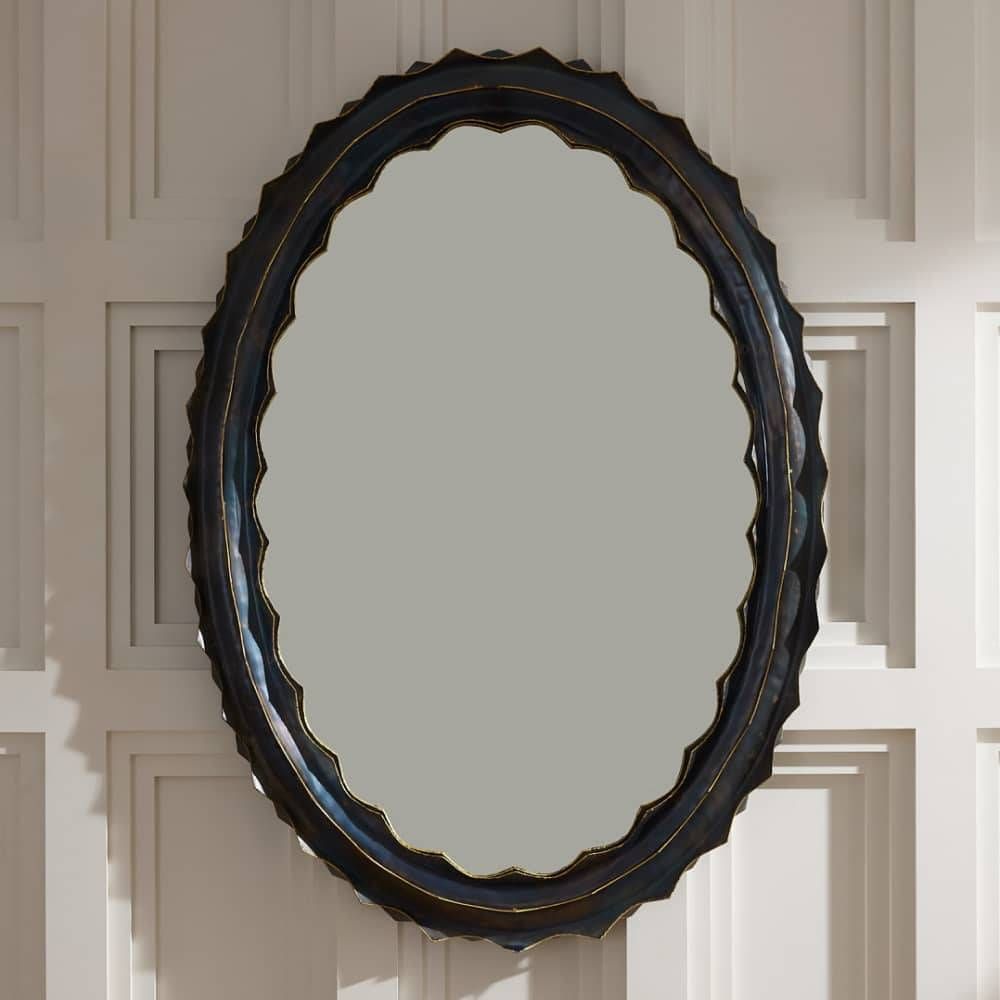 Decorative oval mirror with a black frame on a paneled wall.