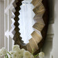 Decorative wall mirror with geometric pattern and white flowers in the foreground