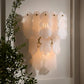 Decorative wall light fixture with a soft glow, surrounded by greenery.