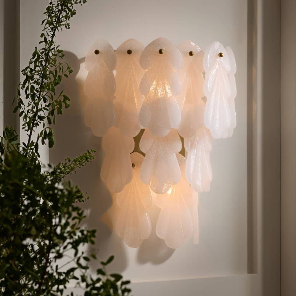 Decorative wall light fixture with a soft glow, surrounded by greenery.